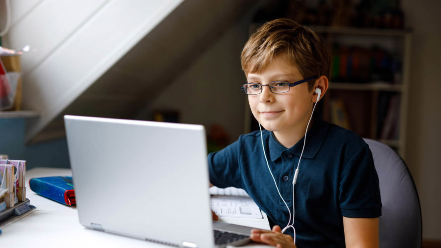 En ung dreng, der sidder med høretelefoner foran sin bærbar